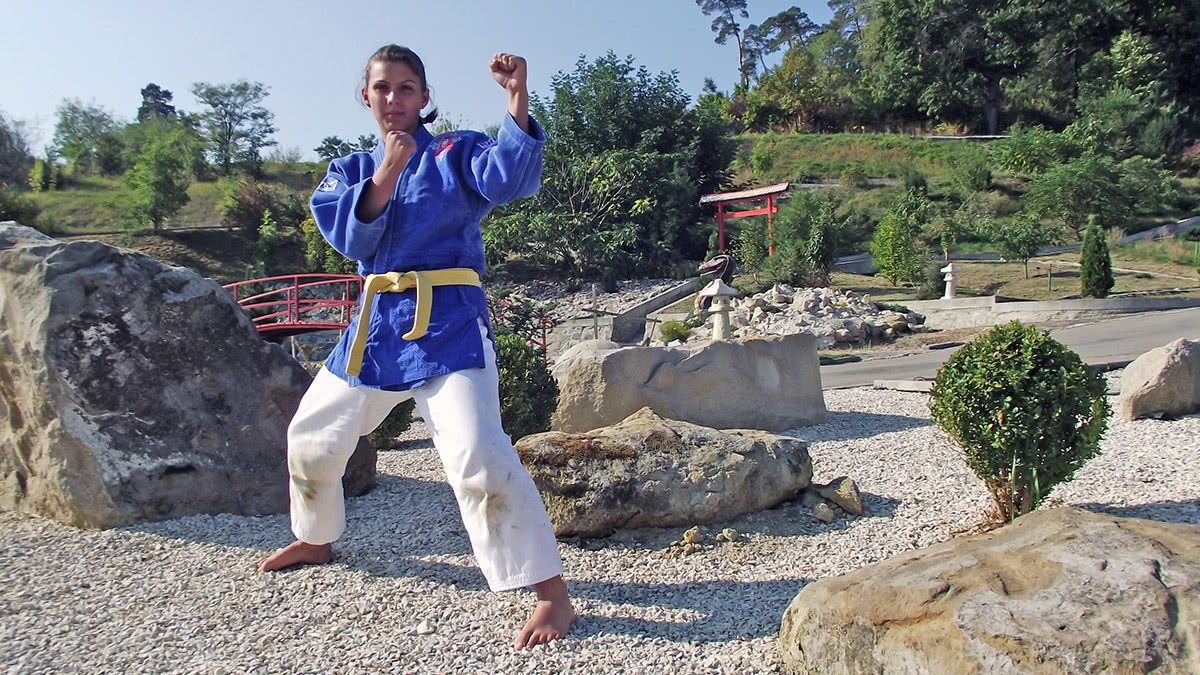 Sportiv cu centură albastră în gardă, în grădina cu pietre